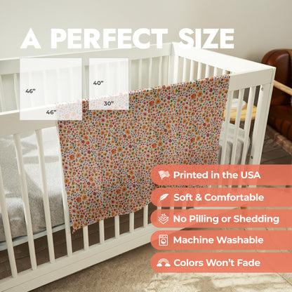 Printed floral pattern baby swaddle draped over crib with product size chart and product features list.