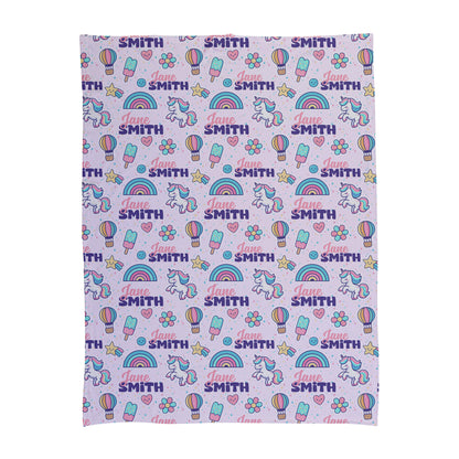 Personalized baby swaddle with unicorns, rainbows and name on light purple and pink background.